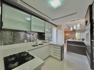 Cozinha moderna com armários brancos e bancadas escuras.