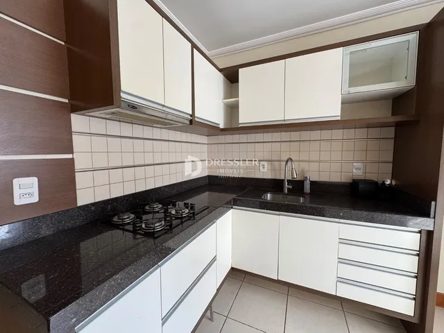 Foto de uma cozinha com armários brancos e bancada escura.