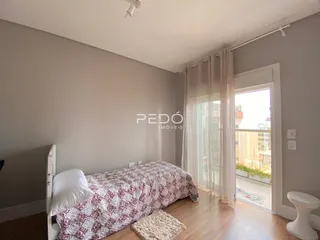 Quarto com cama e piso de madeira clara.