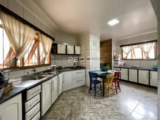 Foto de uma cozinha com armários brancos e piso de cerâmica em um imóvel no Brasil.
