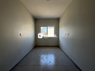 Corredor com piso de cerâmica e janela no final da sala.