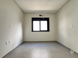 Foto de um corredor interno com paredes brancas e piso de concreto.