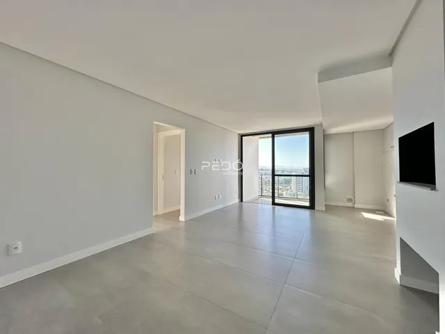 Uma sala de estar ampla com piso de concreto e vista da cidade.