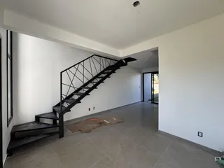 Foto de um corredor com escadaria preta em uma residência.