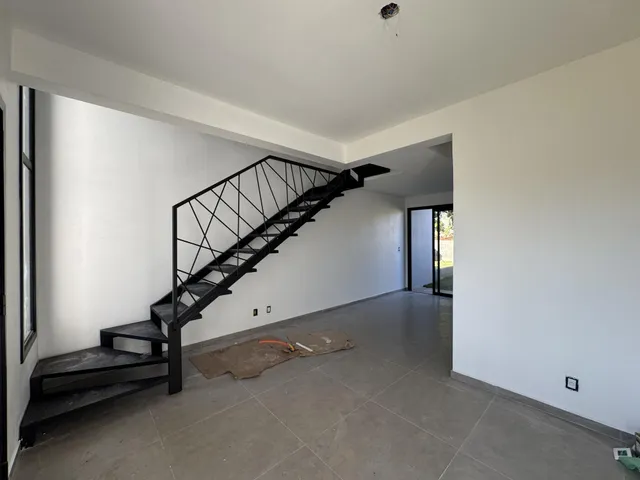 Foto de um corredor com escadaria preta em uma residência.