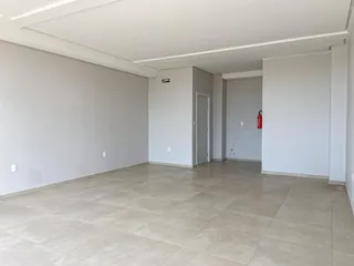Foto de um ambiente interno amplo com paredes brancas e piso de cerâmica clara.