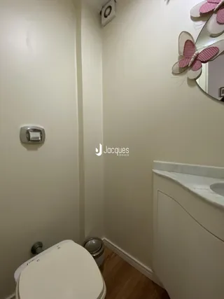 Foto de um banheiro com vaso sanitário e bancada branca.