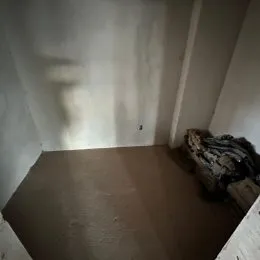 Foto de um interior com paredes brancas e piso marrom.