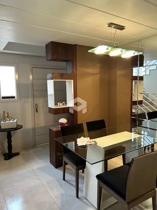 A sala de jantar com mesa de vidro e cadeiras escuras.