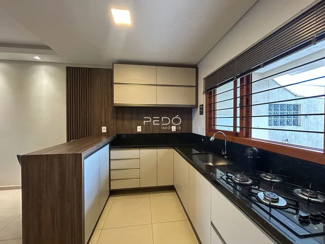 Uma cozinha moderna com armários de madeira e bancadas escuras.