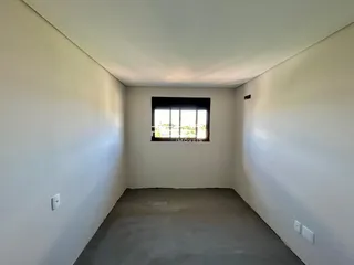 Foto de um cômodo interno vazio com paredes brancas e piso de concreto.