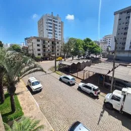 Vista externa de um imóvel com palmeiras e edifícios ao fundo.