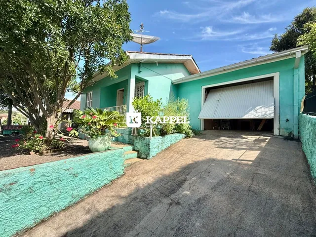 Fachada de uma casa verde-água com jardim e garagem.