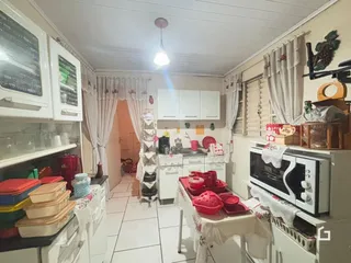 Foto de uma cozinha com armários brancos e piso claro em uma residência.