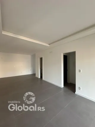Uma sala ampla com paredes brancas e piso cinza.