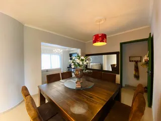 Uma sala de jantar com mesa de madeira e cadeiras em um ambiente interno.