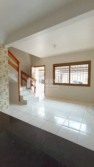 Vista interna de um corredor com piso de cerâmica e escadaria em uma residência.