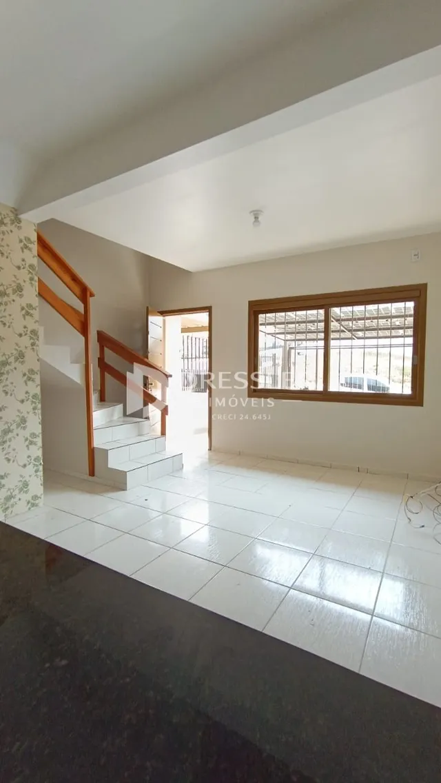 Vista interna de um corredor com piso de cerâmica e escadaria em uma residência.