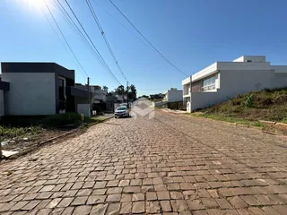 Vista da rua de paralelepípedos entre duas residências modernas.