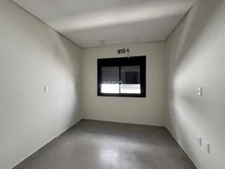 Foto de um corredor interno de uma residência com paredes brancas e piso cinza.