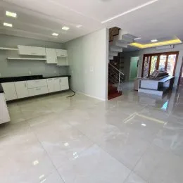 Sala de estar ampla com piso claro e armários brancos na parede.