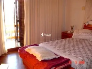 Quarto com cama coberta por edredom branco e vermelho.