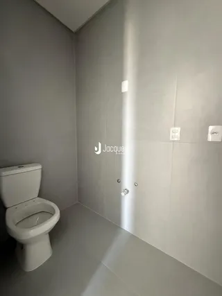 Foto de um banheiro interno com piso claro e vaso sanitário branco.