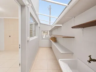 Corredor interno com piso de cerâmica e teto de claraboia.