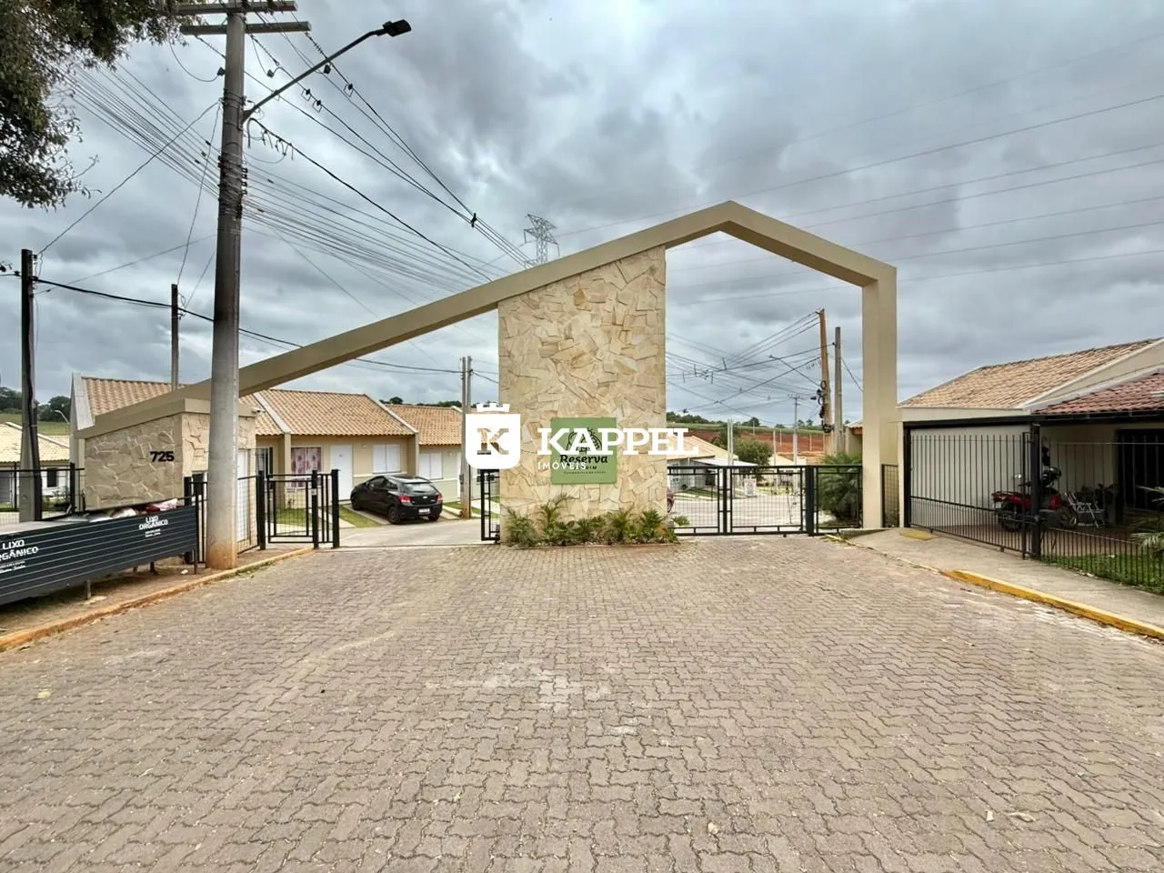 A foto mostra a entrada de uma propriedade com um portão de pedra.