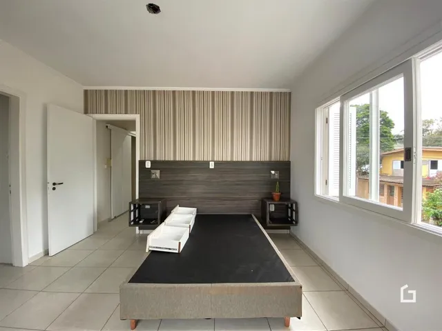 Quarto com cabeceira de madeira e janela de grande porte em um imóvel no Brasil.