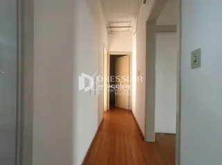 Corredor interno com piso de madeira clara em uma residência.