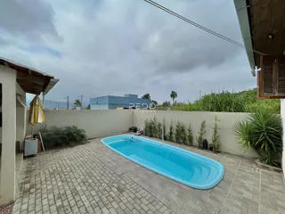Piscina azul em área externa com piso de tijolos.