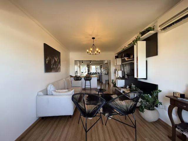 Sala de estar com sofá branco e piso de madeira em um imóvel em Lajeado.