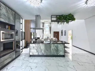 Vista de uma cozinha moderna com piso de mármore claro e ambiente amplo.