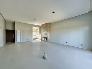 Ambiente interno amplo com piso claro e parede de pedra.