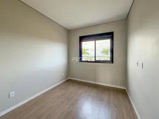 Sala de estar com piso de madeira e grande janela com vista para a paisagem.