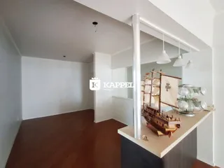 Sala de estar com piso de madeira e paredes brancas.