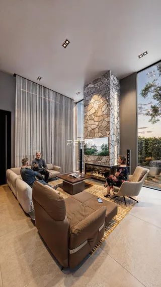 Sala de estar moderna com lareira de pedra e grandes janelas.