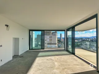 Vista interna de um ambiente com grandes portas de vidro que dão para uma paisagem urbana.