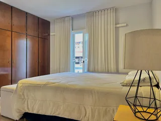 Quarto com armários de madeira e cama bem iluminado.