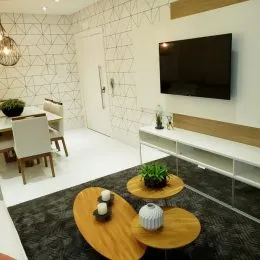 Foto de uma sala de estar com um tapete escuro e uma televisão na parede.