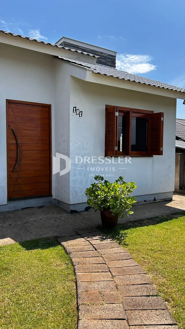 Fachada de uma casa em Lajeado, Brasil, com porta de madeira e jardim na frente.