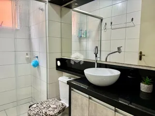 Banheiro com box de vidro e bancada escura.