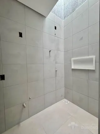 Hall de corredor com paredes de azulejo cinza claro.