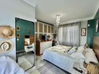 Quarto com cama e espelho refletindo outro ambiente.