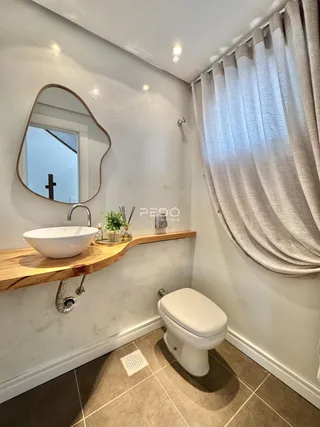 Banheiro com pia de apoio e vaso sanitário em um ambiente claro.