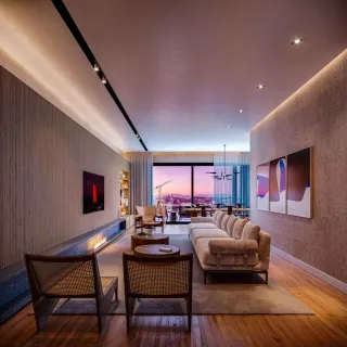 Sala de estar moderna com sofá e vista noturna da cidade.