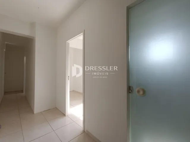 Hall de entrada com piso de cerâmica e paredes brancas.