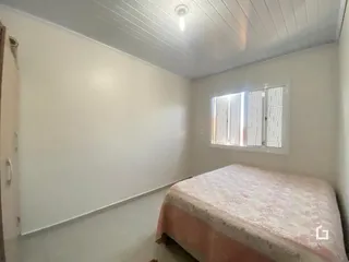 Quarto com cama e janela em ambiente claro.