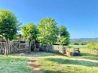 Vista externa de uma propriedade com cerca de madeira e vegetação.